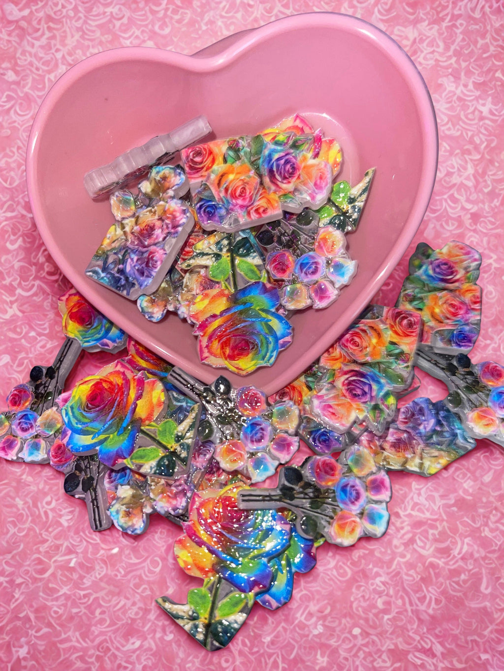 Rainbow rose beads in pink heart bowl on pink swirl background
