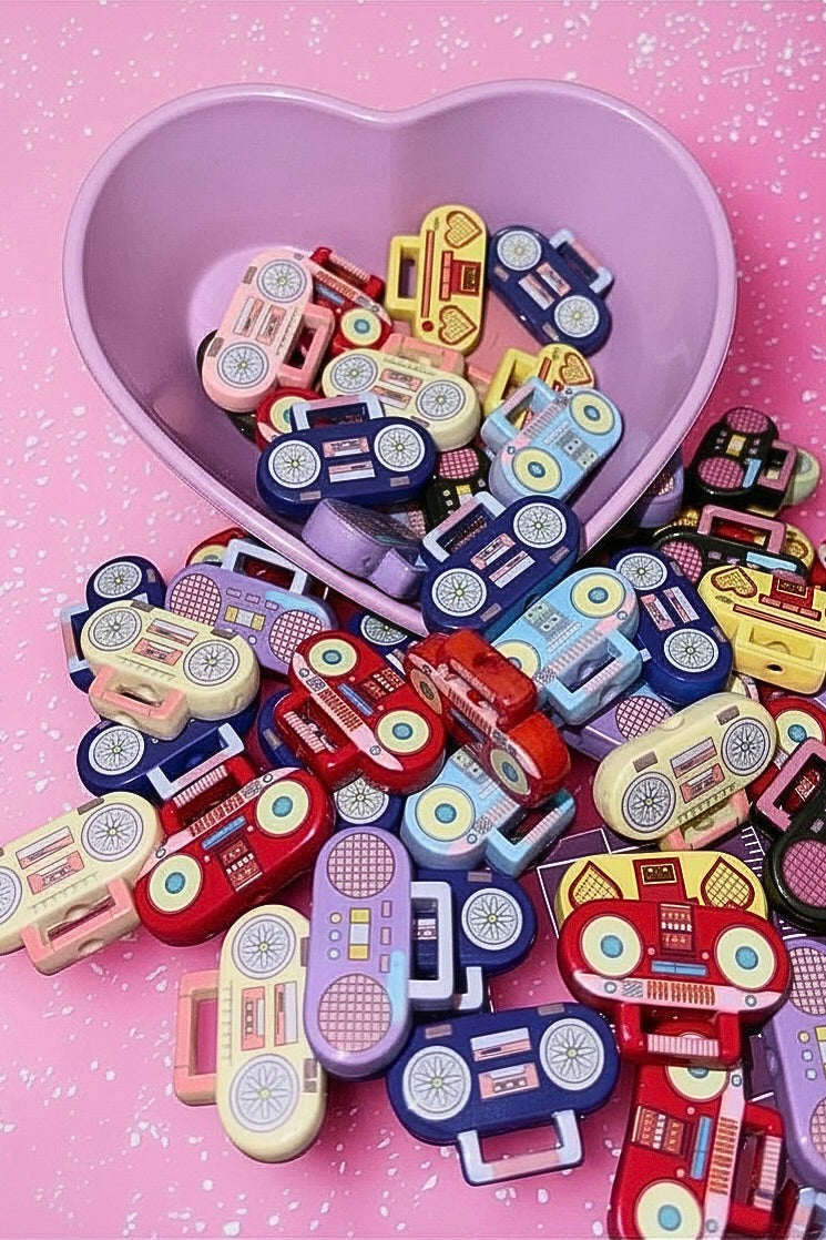 Mixed color retro boombox beads in a purple heart bowl on pink background