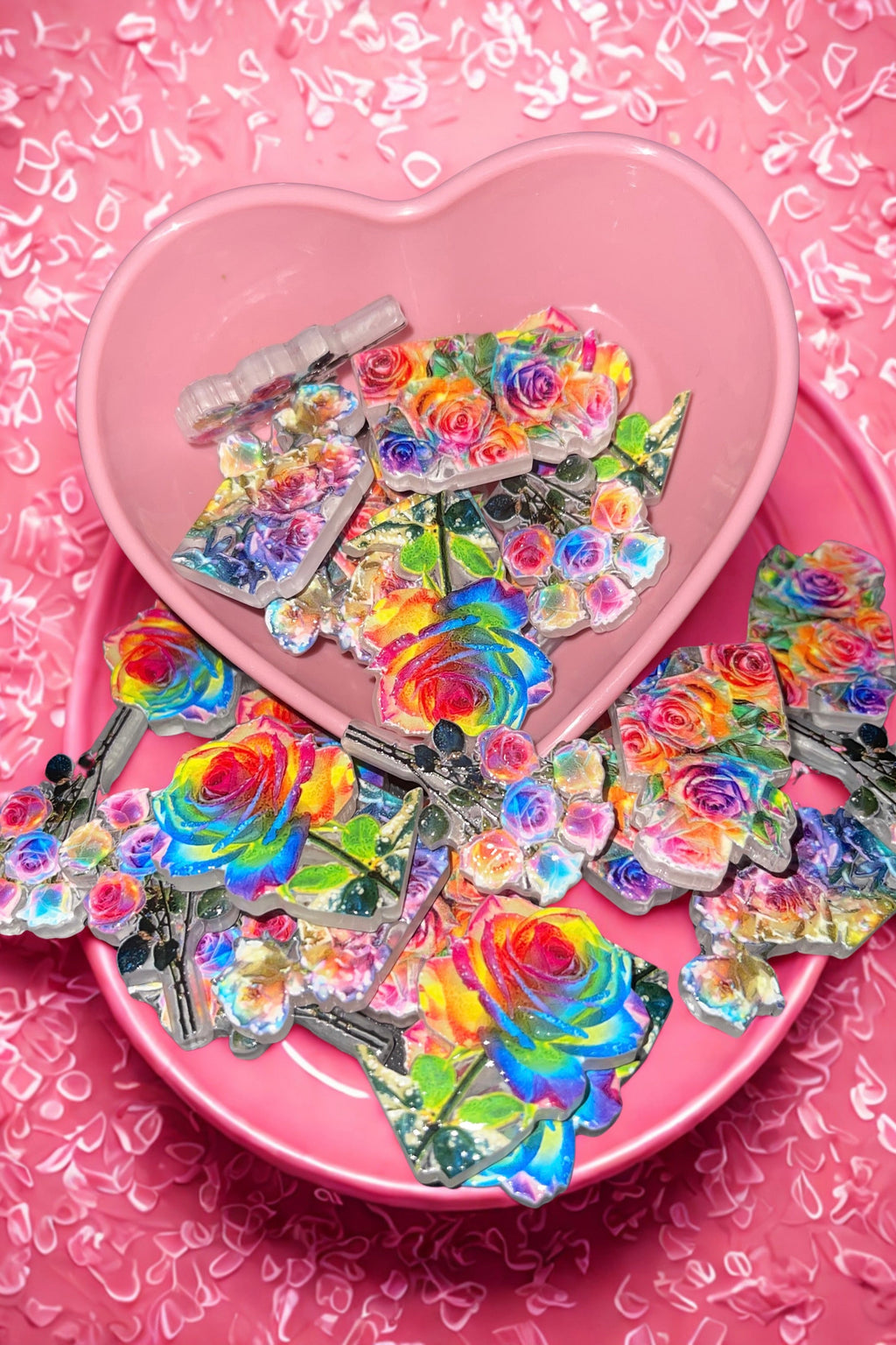 Rainbow rose beads in pink heart bowl on pink confetti background
