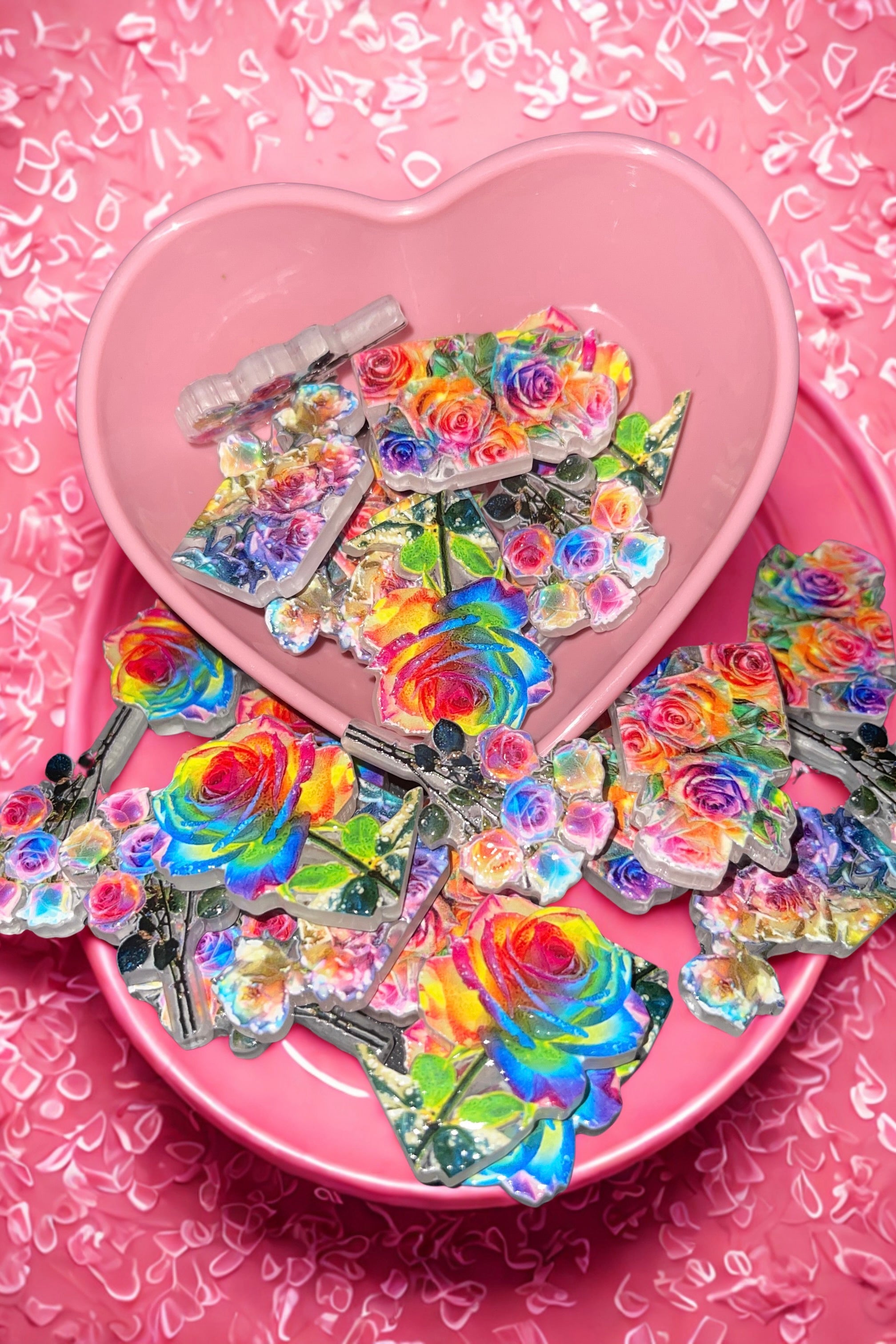 Rainbow rose beads in pink heart bowl on pink confetti background