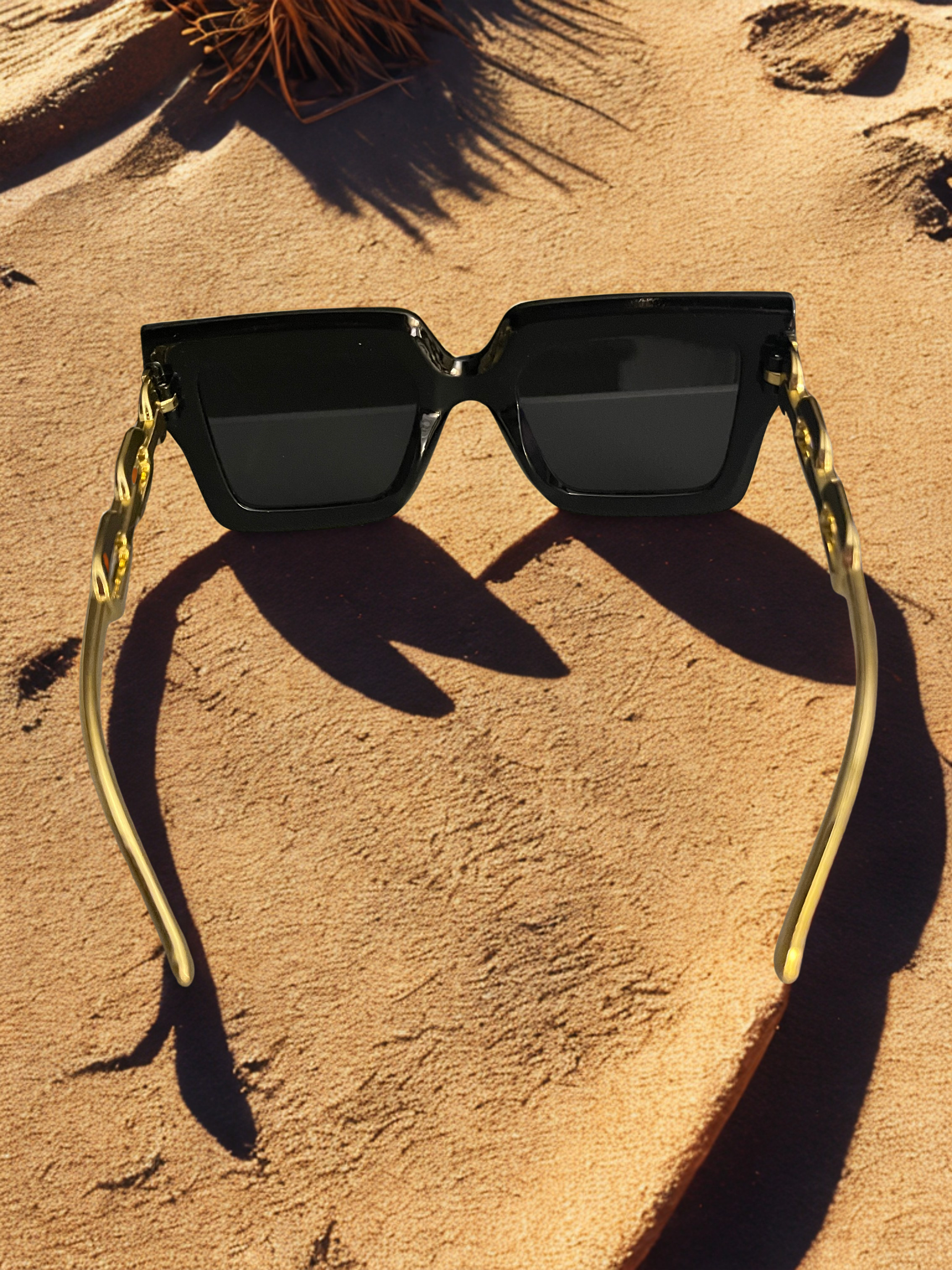 Chain Reaction Sunglasses laying on sand showing chain detail
