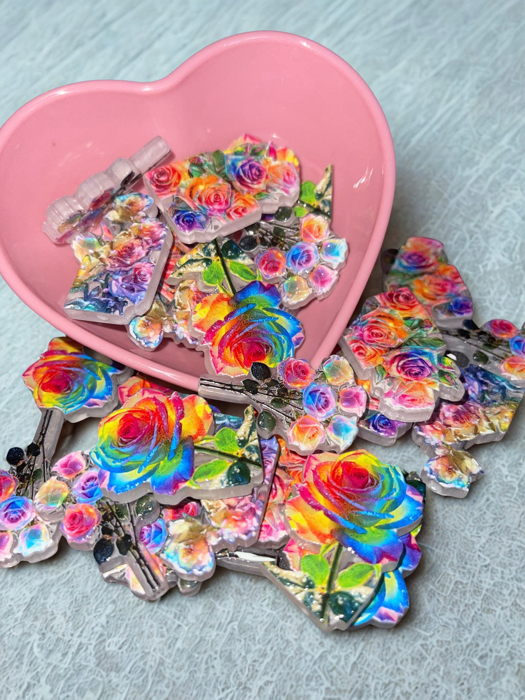 Holographic rainbow rose beads spilling from pink heart bowl on white lace