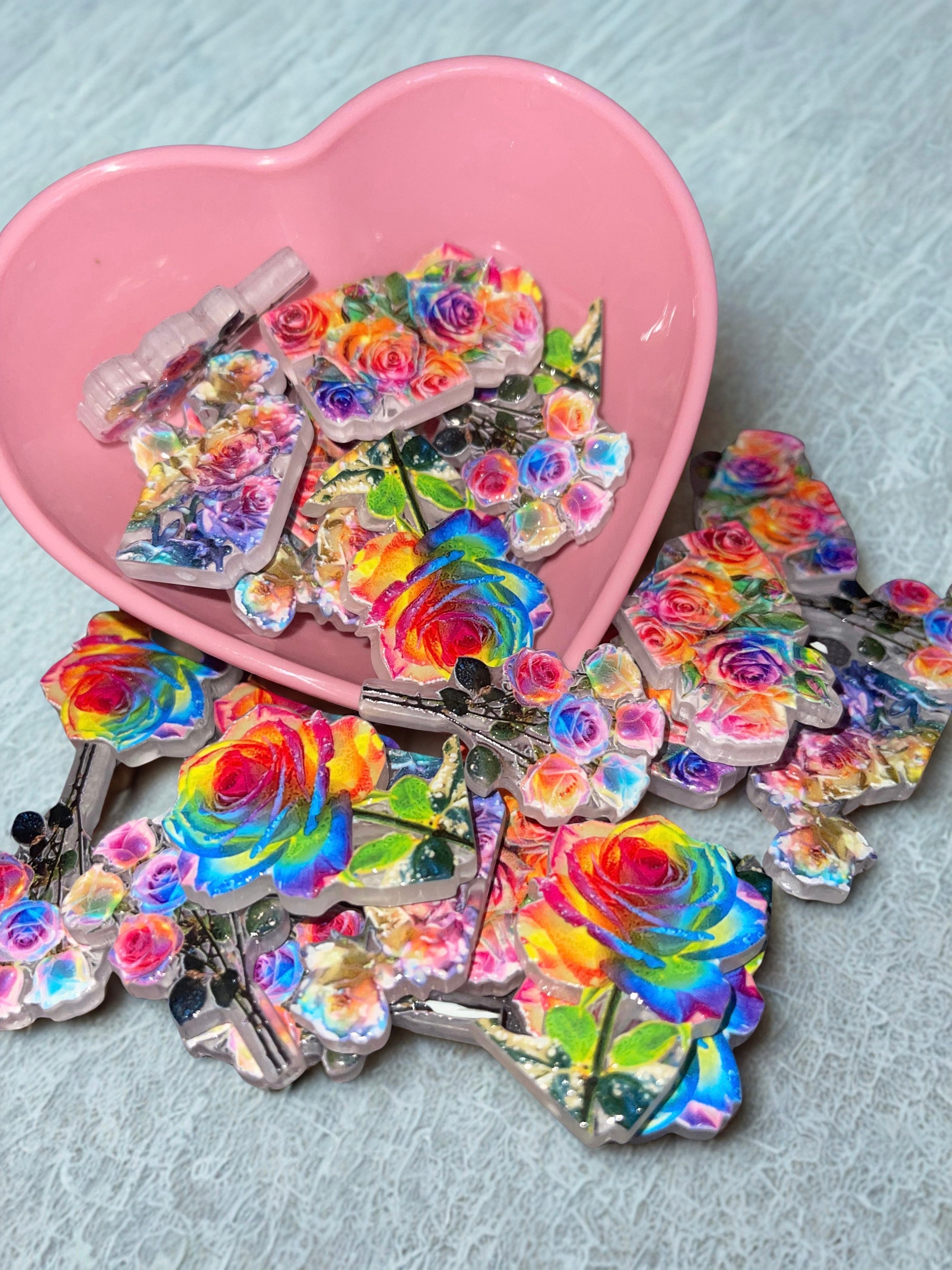 Holographic rainbow rose beads spilling from pink heart bowl on white lace