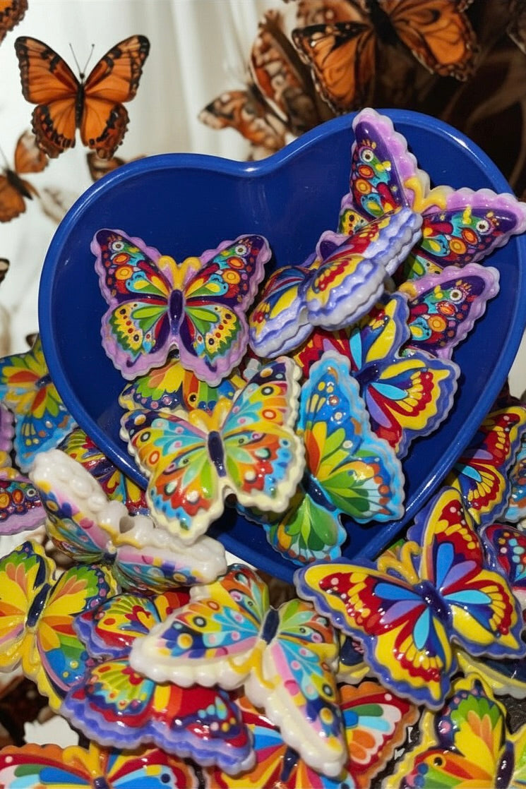 Large rainbow butterfly beads in a blue heart bowl on butterfly print background