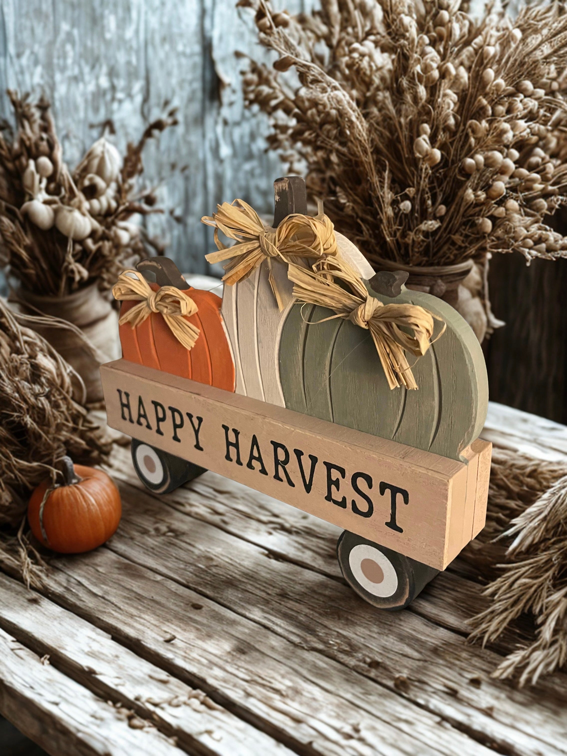 Happy Harvest pumpkin wagon sitter on rustic wood table with dried botanicals