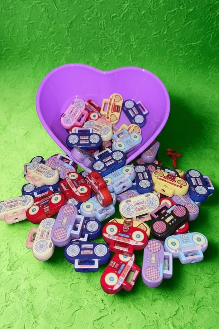 Assorted boombox beads in a purple heart bowl on green background