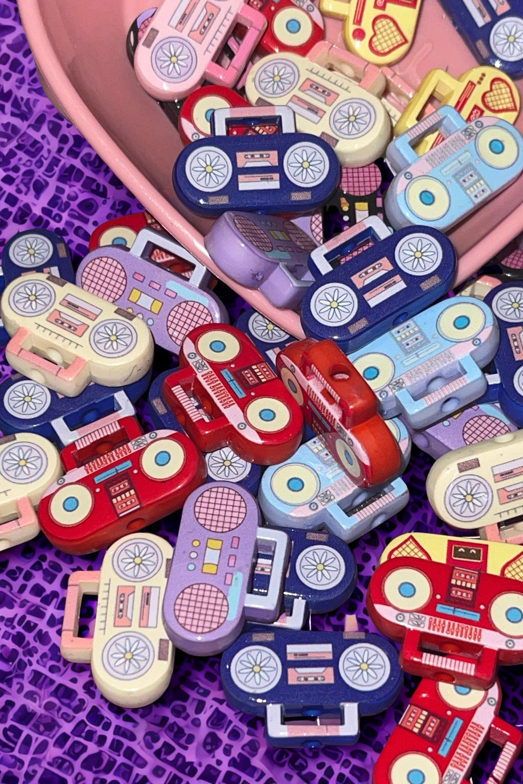 Colorful retro boombox beads spilling from a pink bowl on purple lace background